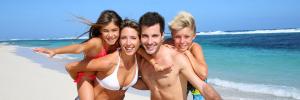 Famiglia felice in spiaggia, genitori e figli sorridenti.